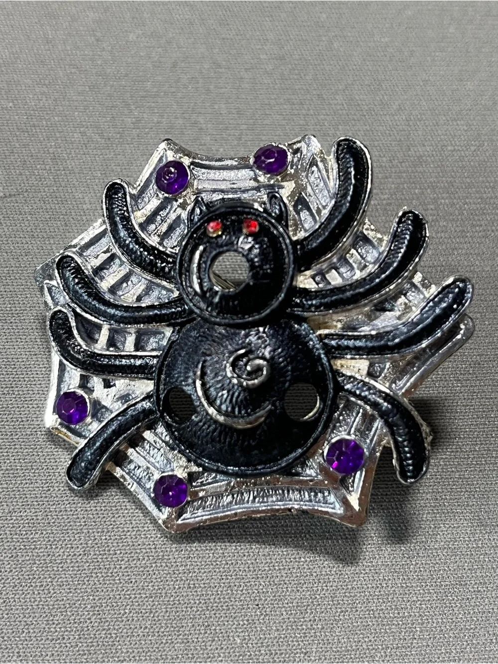 Spooky silver and black metal spider pin for Halloween.